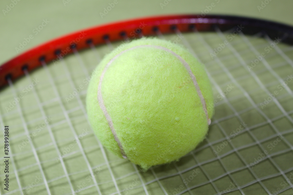 Tennis racket with ball on a green background