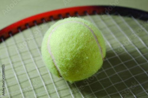 Tennis racket with ball on a green background