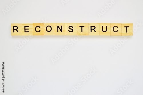Word reconstruct. Wooden blocks with lettering on top of white background. Top view of wooden blocks with letters on white surface