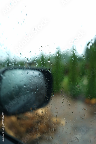 Car mirror, raindrops, blurred green background
