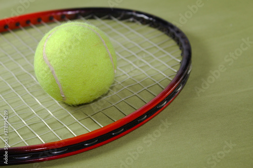 Tennis racket with ball on a green background © Jos