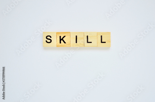 Word skill. Wooden blocks with lettering on top of white background. Top view of wooden blocks with letters on white surface
