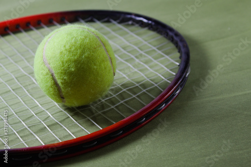 Tennis racket with ball on a green background © Jos
