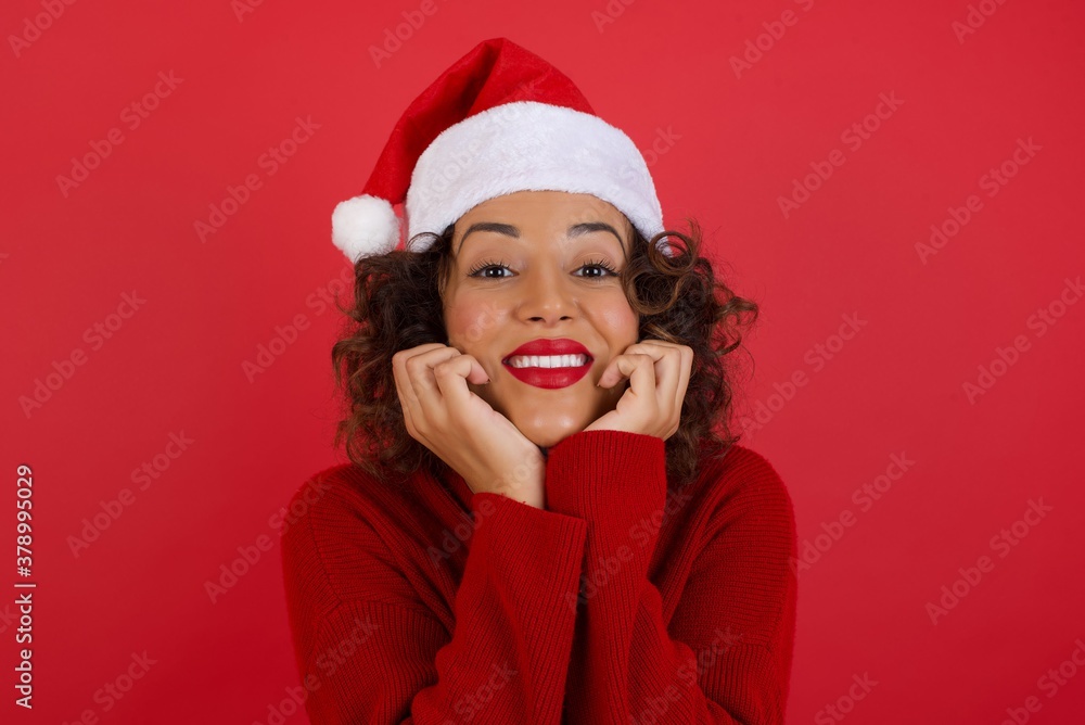 Dreamy young European woman keeps hands pressed together under chin, looks with happy expression, has toothy smile, isolated over gray background Dreamy young European woman keeps hands pressed together under chin, looks with happy expression, has toothy smile, isolated over gray background