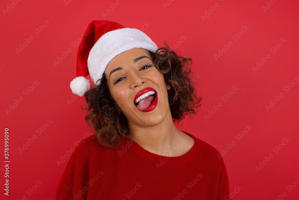 Beautiful caucasian woman with happy and funny face smiling and showing tongue. Wearing casual clothes and standing against white studio background. Beautiful caucasian woman with happy and funny face smiling and showing tongue. Wearing casual clothes and standing against white studio background.