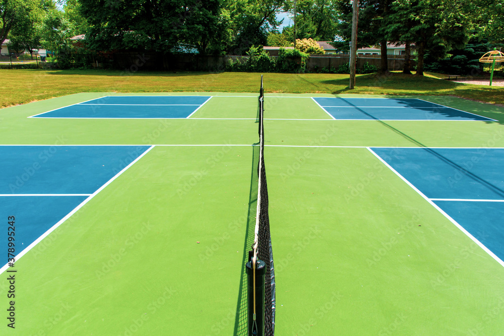 Fototapeta premium Recreational sport of pickleball court in Michigan, USA looking at an empty blue and green new court at a outdoor park. Middle Court View.