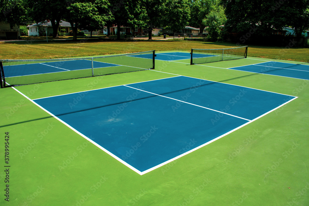 Recreational sport of pickleball court in Michigan, USA looking at an empty blue and green new court at a outdoor park.