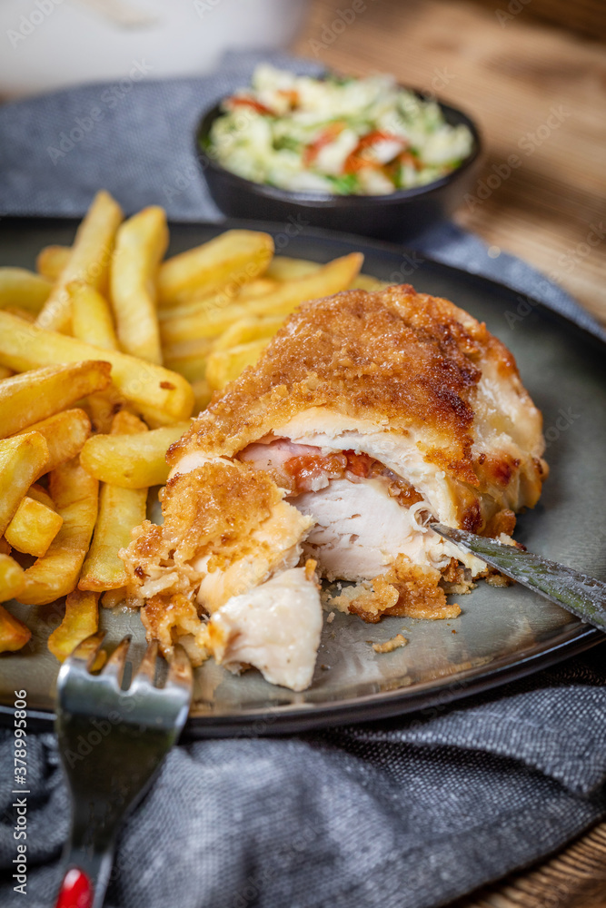 Fried chicken breast stuffed with bacon and cheese served with chips and salad. Fried chicken breast stuffed with bacon and cheese served with chips and salad.