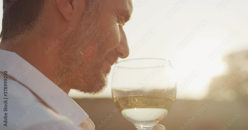 Authentic shot of happy handsome elegantly dressed man is tasting a flavor and drinking fresh white wine poured in transparent glass on scenic vineyards background at sunset. Authentic shot of happy handsome elegantly dressed man is tasting a flavor and drinking fresh white wine poured in transparent glass on scenic vineyards background at sunset.