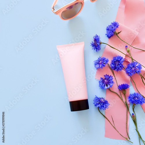 Bottle for branding and label. Mockup / 3d model of pink squeeze bottle plastic tube with black cap, blue flowers, pink ribbons and sunglasses . Top view. Natural organic spa cosmetics concept.