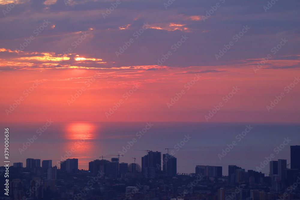 Reflections of the sunlight over the sea with group of skyscrapers and construction area in foreground