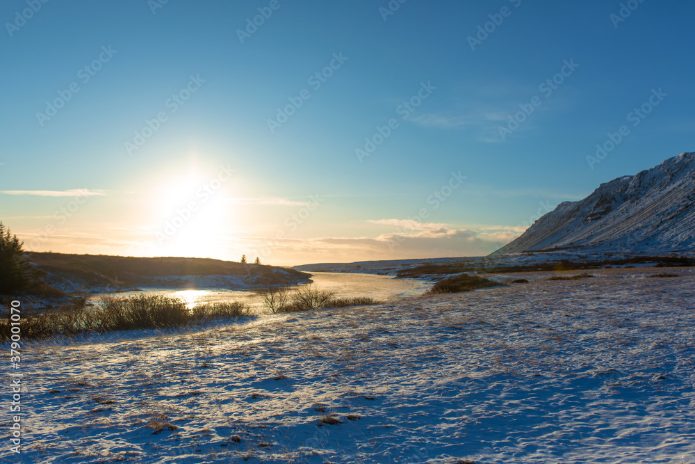 River on the plain in Iceland. The banks are covered with snow. Winter landscape, open spaces.