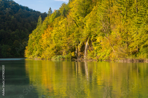Fototapeta Naklejka Na Ścianę i Meble -  Colorful autumn trees reflecting in a lake. Colorful autumn forest by the lake. Beautiful autumnal park.