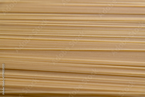 Abstract food background of raw uncooked spaghetti pasta made from milled durum wheat. Selective focus. Copy space for your text. Italian cuisine theme.