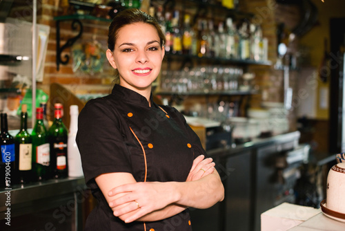 Pretty waitress posing in restaurant bar looking at camera