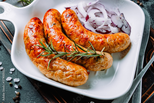  Hot fried sausages with rosemary and onions close-up
