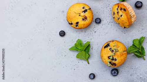 Фотография Fresh homemade delicious blueberry muffins decorated with thyme, fresh berries and mint on grey concrete background