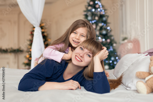 Little girl spends time playing with mom while lying in bed. Christmas tale. Happy childhood