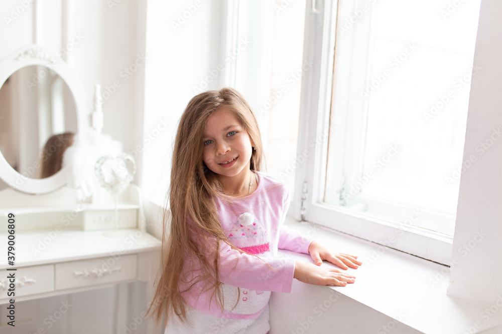 Portrait of a beautiful teenage girl stands by the white window Portrait of a beautiful teenage girl stands by the white window