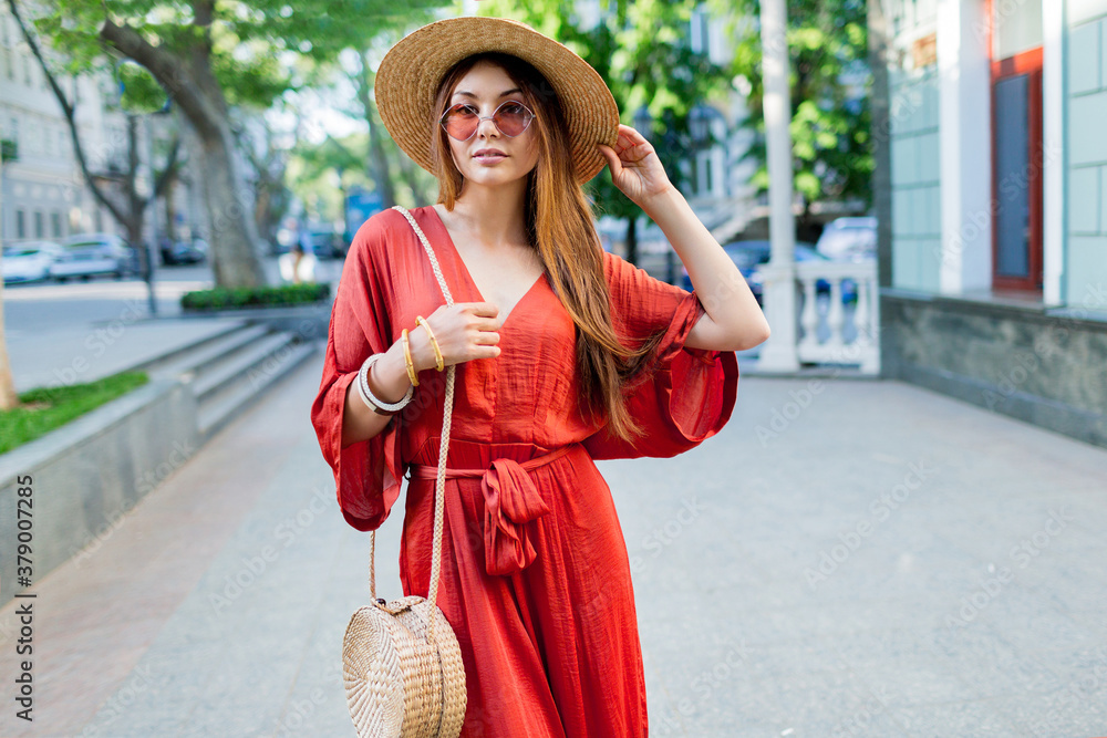Elegant gorgeous  lady in coral long dress walking outdoor. Bright summer colors.  Fashionable street look.