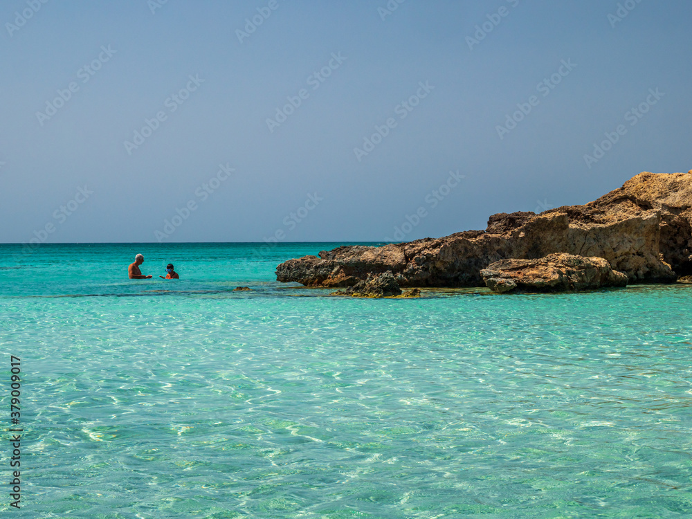 Elafonisi Crete Beach view to crystal clear water with nature rocks at the background
