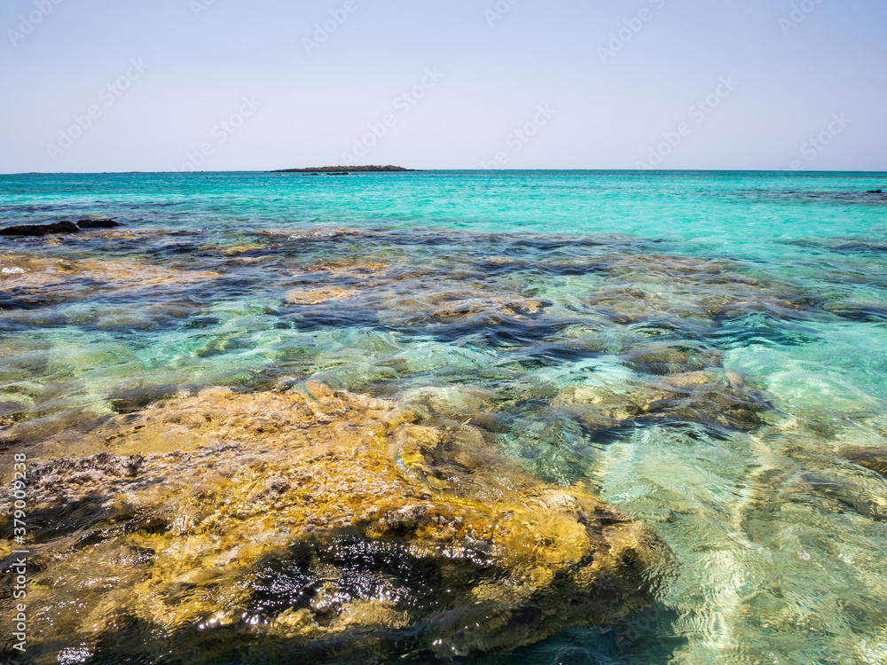 Elafonisi Crete Beach view to crystal clear water with nature rocks at the background Elafonisi Crete Beach view to crystal clear water with nature rocks at the background