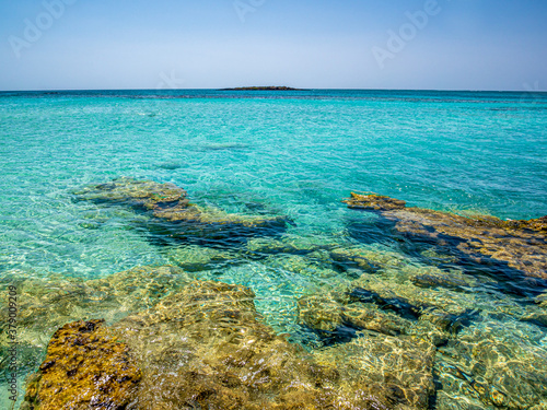 Elafonisi Crete Beach view to crystal clear water with nature rocks at the background