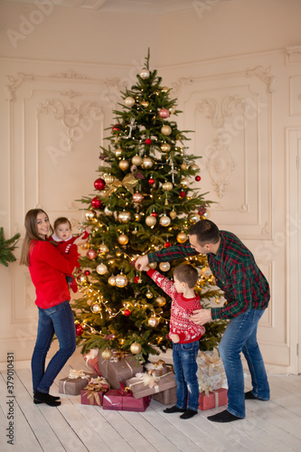 Happy family decorate the Christmas tree indoors together. Loving family. Merry Christmas and Happy Holidays © Kate