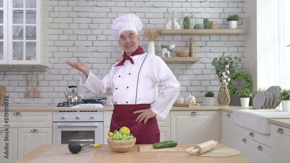 Elderly male chef posing in the kitchen Elderly male chef posing in the kitchen