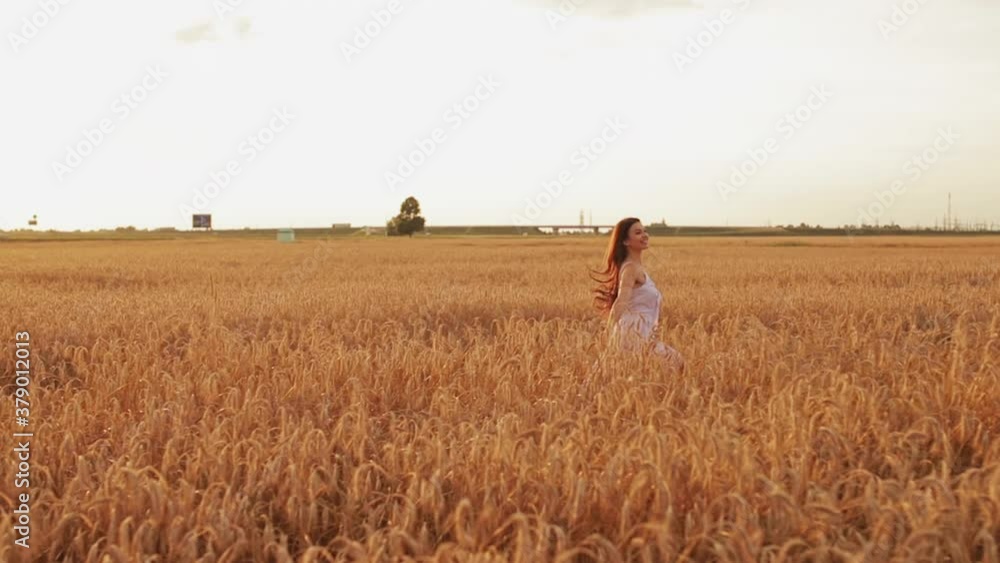 Attractive and cheerful caucasian woman with long dark wavy hair in a long white dress runs across the field and has fun Attractive and cheerful caucasian woman with long dark wavy hair in a long white dress runs across the field and has fun
