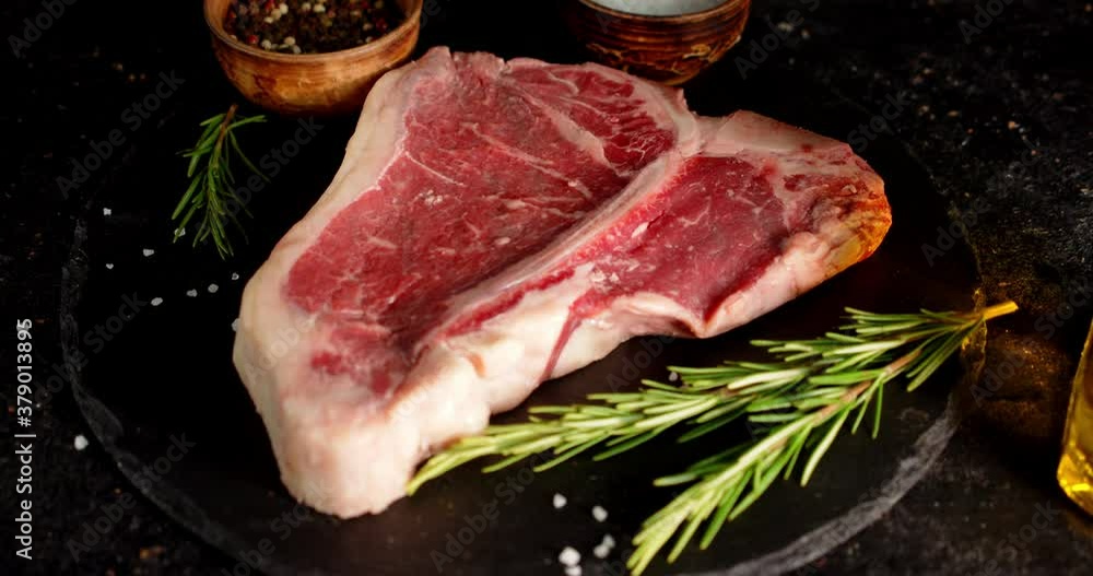 Steak raw beef t-bone on a stone board with spices. Steak raw beef t-bone on a stone board with spices.
