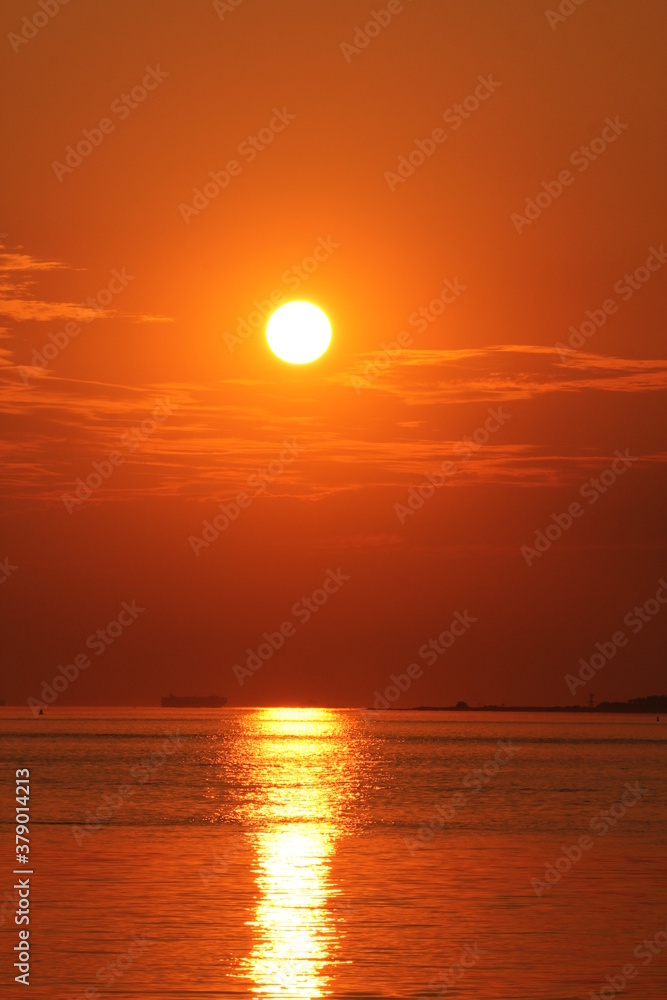a beautiful sunset at the dutch coast at a warm summer evening with an orange sky and water of the westerschelde sea with a sunbeam