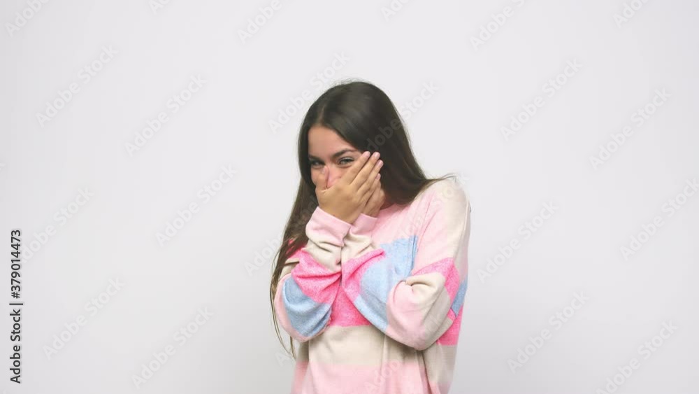 Young cute woman blink at the camera through fingers, embarrassed covering face Young cute woman blink at the camera through fingers, embarrassed covering face