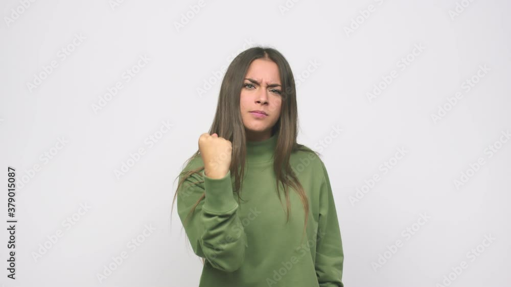 Young cute woman showing fist to camera, aggressive facial expression Young cute woman showing fist to camera, aggressive facial expression