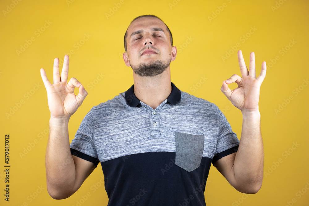 Russian man standing over insolated yellow background relax and smiling with eyes closed doing meditation gesture with fingers. Yoga concept. Russian man standing over insolated yellow background relax and smiling with eyes closed doing meditation gesture with fingers. Yoga concept.