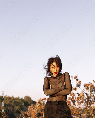 
Girl in black trousers in a field with thorns