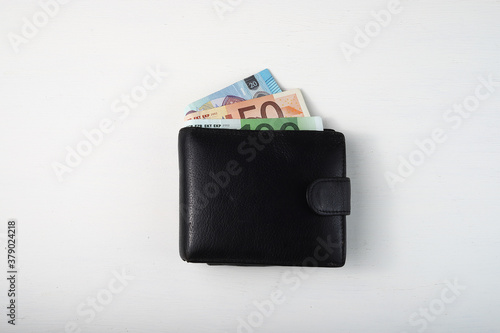 black wallet with euro sticking out on white background