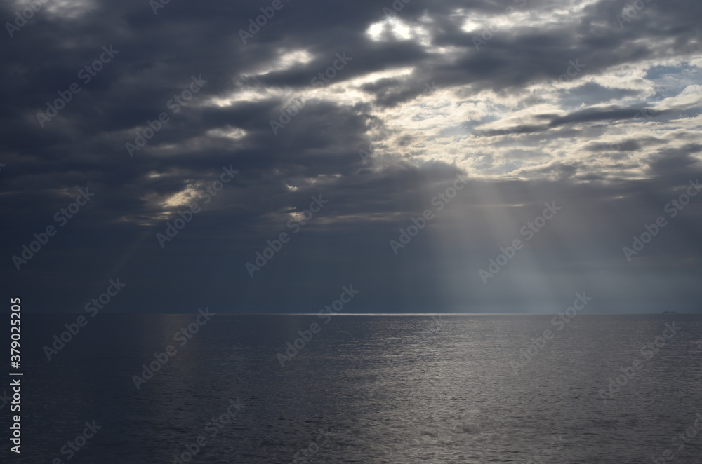 open sea with clouds and sun filtering through