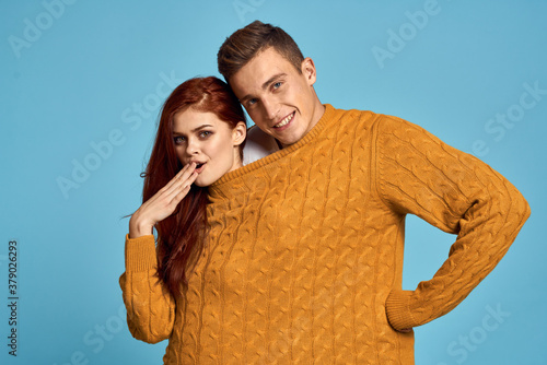 couple in yellow sweater posing against blue background cropped view