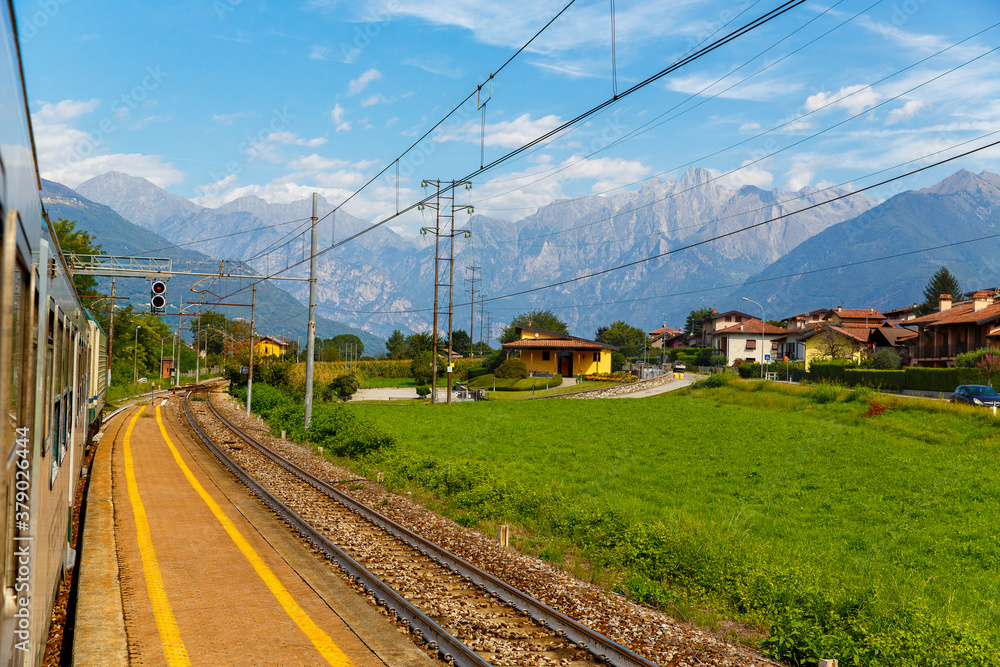 View from a passing train on the landscape of an Italian village on the background of the Alps. View from a passing train on the landscape of an Italian village on the background of the Alps.