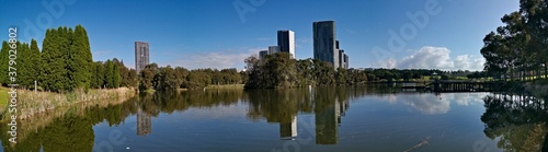 Beautiful panoramic view of a lake with reflections of luxury high-rise building, blue sky, clouds, and trees on water, lake Pavillion, Sydney Olympic park, Sydney, New South Wales, Australia 