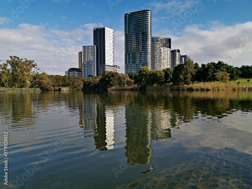 Beautiful view of a lake with reflections of luxury high-rise building, blue sky, clouds, and trees on water, lake Pavillion, Sydney Olympic park, Sydney, New South Wales, Australia 