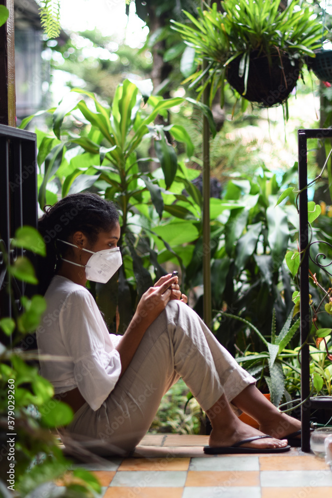 Young black woman in face mask using a smartphone Young black woman in face mask using a smartphone