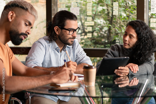 Professional brazilian teammates with tablet collaborating and discussing project plans inside coworking office. Unity  teamwork  collaboration concept..