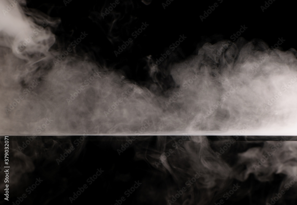 Fototapeta premium White smoke swirling spreads over the surface flowing down from the edges on a black background