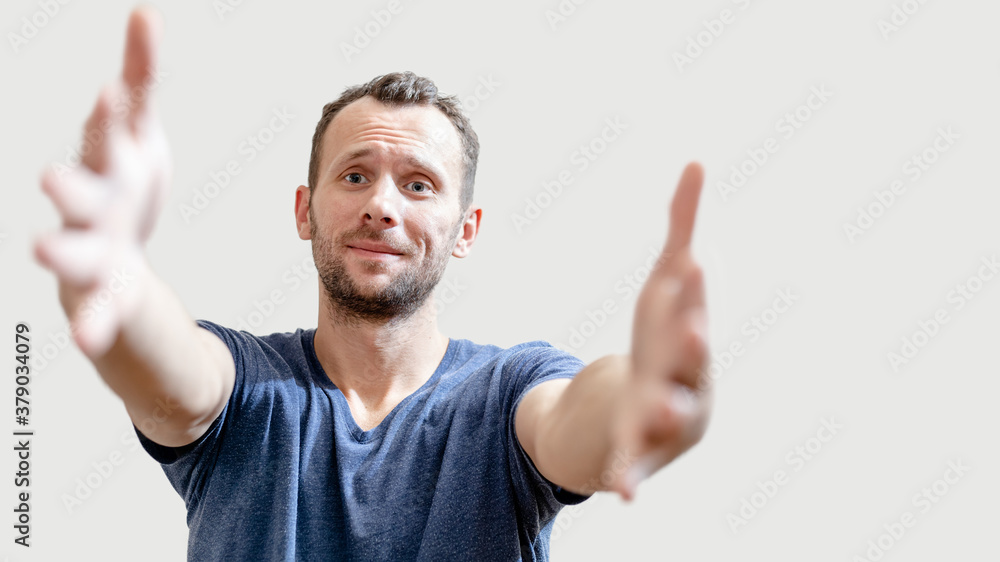 friendly happy man pulls his hands to the camera for a hug on gray background with copy space friendly happy man pulls his hands to the camera for a hug on gray background with copy space