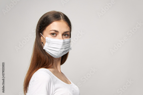 Woman with a medical mask on her face in a white brunette t-shirt Copy Space