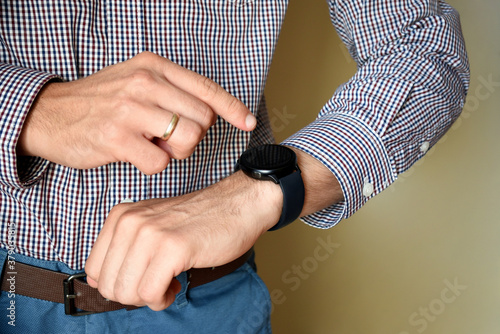 Male hands touching screen and using his smart watch app. Close-up hands