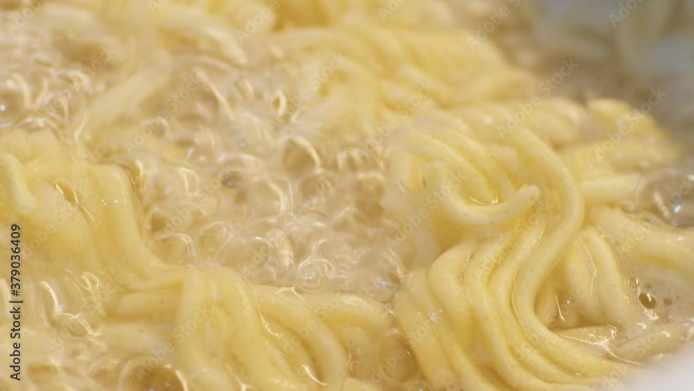 Instant Ramen Noodles Cooked In A Boiling Water With Bubbles. - macro shot, slow motion Instant Ramen Noodles Cooked In A Boiling Water With Bubbles. - macro shot, slow motion