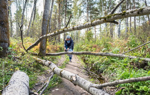 A woman tying shoelaces on a forest path among the trees felled by the storm